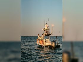 A group of friends enjoys a fishing trip on a boat during sunset, capturing the essence of adventure and camaraderie on the water.