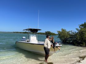 A joyful moment between a parent and child by the boat on a beautiful beach, capturing the essence of family fun and adventure on the water.