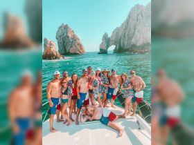 A lively group enjoys a fun day on the boat in Cabo San Lucas, showcasing camaraderie and celebration against a stunning coastal backdrop.