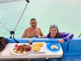 A couple enjoys a delicious spread of fruits and snacks on a boat, perfect for a relaxing day on the water.
