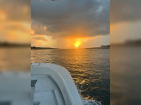 A stunning sunset view from the bow of a boat, capturing the golden hues reflecting on the water — perfect for serene evening cruises.