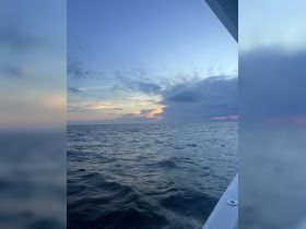 A serene view of the ocean at sunset, showcasing the tranquil waters and colorful sky, perfect for capturing the beauty of a boating experience.
