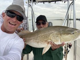 Two anglers proudly display their catch while enjoying a fishing trip on the water — a perfect moment of camaraderie and celebration.
