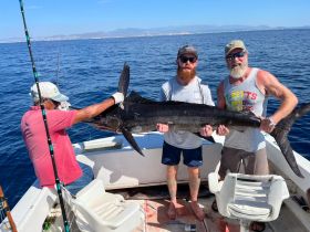 A group of anglers proudly display their impressive catch aboard a fishing boat, showcasing the thrill of deep-sea fishing adventures.