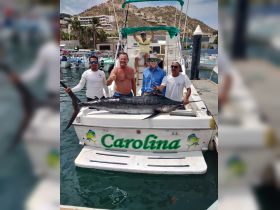 A group of fishermen proudly displays their catch of a marlin aboard the boat 'Carolina' — a memorable moment celebrating a successful fishing trip.