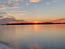A scenic view of a sunset over calm waters, though the image is slightly unclear.
