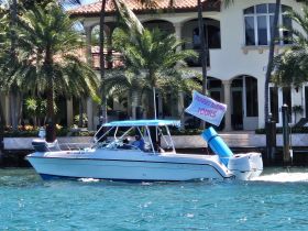 A speedboat named 'Glacier Bay' is seen cruising along the waterfront, promoting 'Perfect Timing Tours' — an ideal choice for exploring scenic waterways.