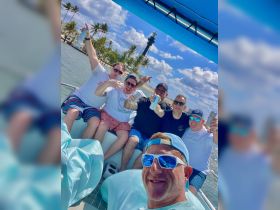 A lively group of friends celebrates aboard a boat with drinks in hand, capturing the fun of their day on the water.