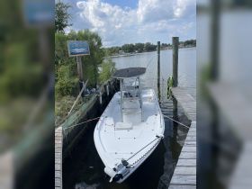A center console boat docked at a serene waterfront location, perfect for fishing or leisurely outings. Contact for rental information is available.