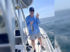A fisherman proudly displays his catch aboard a boat in the ocean, showcasing the thrill of a successful fishing trip.