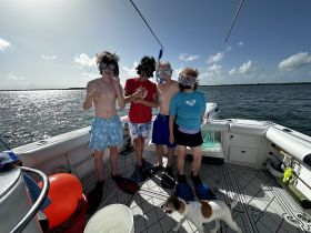 A group of excited snorkelers prepares for an underwater adventure on a boat, with a playful dog joining the fun — perfect for family outings and aquatic exploration.