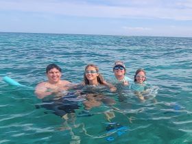 A joyful family enjoys a snorkeling adventure in crystal-clear waters, showcasing the fun of swimming together in a tropical paradise.