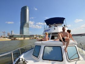 A lively group enjoys a sunny day on a boat, soaking up the city views and celebrating together — perfect for a fun outing on the water.