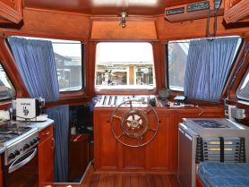 Interior view of a boat's helm and cabin area, showcasing the wooden finishes and navigational equipment — perfect for those interested in boat design and functionality.