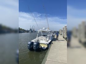 A sleek speedboat docked at the marina, showcasing its powerful twin engines and spacious layout, perfect for fishing or cruising.