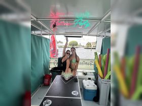 Two friends celebrate on a pontoon boat, enjoying colorful cocktails and a lively atmosphere — perfect for a fun day on the water.