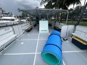 Interior view of a spacious boat cabin featuring seating and a rolled-up floating mat, ideal for group outings or water activities.