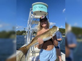 A young woman proudly displays her catch while fishing on a boat named 'Dorado' — a perfect moment celebrating a successful day on the water.