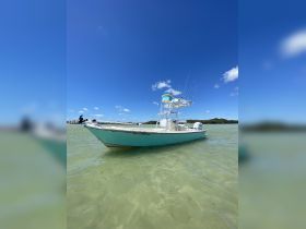 A sleek speedboat anchored in clear waters under a bright blue sky, perfect for fishing or leisurely outings.