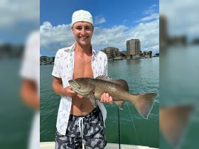 A young man proudly displays his catch while fishing on a boat, showcasing a successful day on the water. Perfect for fishing enthusiasts and adventure seekers.