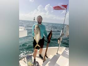 A proud angler displays his catch while fishing in the ocean, showcasing the thrill of spearfishing adventures.