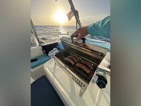 A close-up of sausages grilling on a boat's BBQ as the sun sets over the horizon, perfect for a delicious meal on the water.