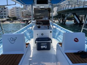 A well-equipped helm area of a boat featuring stylish seating and a cooler, perfect for a day on the water.