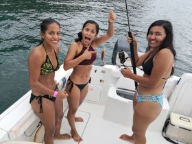 Three friends celebrate their fishing catch aboard a boat, showcasing the excitement of a fun day on the water.