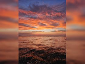 A breathtaking sunset paints the sky in vibrant hues over calm waters, creating a serene backdrop perfect for evening boat cruises.