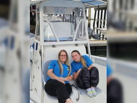 Two friends relax on the deck of a boat, enjoying a moment together. Perfect for showcasing camaraderie and leisure on the water.