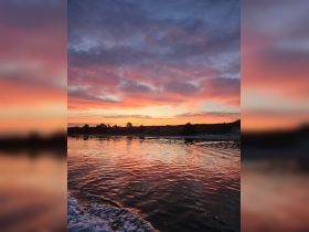 A stunning sunset casts vibrant colors across the water, creating a picturesque scene perfect for evening boat cruises.