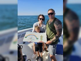 A heartwarming moment on a boat as a family celebrates a special proposal, with a child holding a colorful sign asking if a woman will be their second mom.