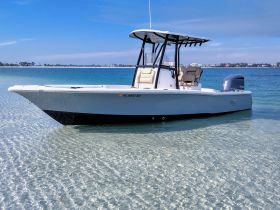 A sleek center console boat anchored in shallow, clear waters, showcasing its elegant design against a picturesque backdrop.