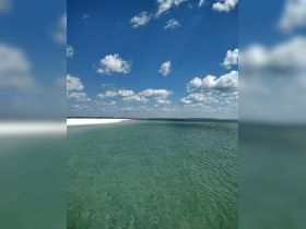 A stunning view of a tranquil beach with clear turquoise waters and a bright blue sky, perfect for showcasing the beauty of coastal destinations.