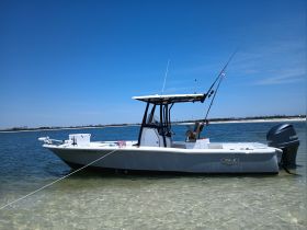 A sleek speedboat anchored in shallow waters under a clear blue sky, perfect for fishing or leisurely outings.