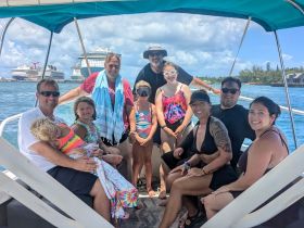 A joyful family gathers on a boat, enjoying their time together with a beautiful backdrop of cruise ships — perfect for memorable outings and celebrations on the water.