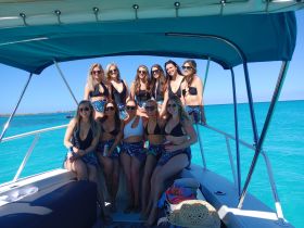 A vibrant group of friends enjoys a sunny day on the boat, showcasing the perfect backdrop of turquoise waters — ideal for celebrations and memorable outings.