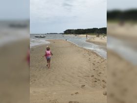 A child joyfully runs along a sandy beach near a boat, capturing the essence of a fun-filled day at the sandbar.