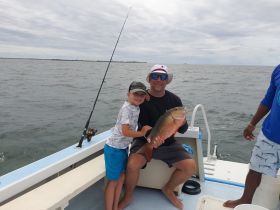 A joyful moment on the water as a father and son proudly display their catch while fishing together — a perfect family bonding experience on a boat.