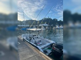 A fishing boat named 'Osmak Fishing' docked at the marina, showcasing its fishing gear and sleek design against a serene waterfront backdrop.