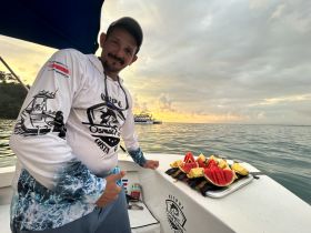 A crew member showcases a vibrant platter of fresh fruit on board, perfect for enjoying while out on the water. Ideal for catering during fishing trips or leisurely boat rides.