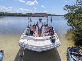 A cheerful group of friends enjoys a sunny day on the water aboard their boat, perfect for creating unforgettable memories together.