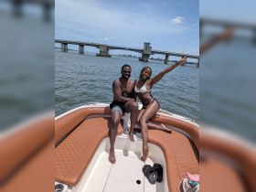 A joyful couple enjoys a sunny day on a boat, capturing a moment of celebration and fun on the water.