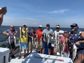 A group of friends proudly displays their catch after a successful fishing trip, showcasing the joy of fishing adventures on the water.