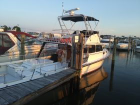 A well-maintained boat docked at a marina, showcasing its sleek design and structure against a serene water backdrop.