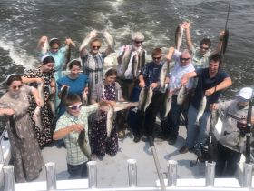 A joyful group displays their catch after a successful fishing trip, showcasing the excitement of fishing adventures on the water.