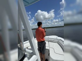 A person stands on the deck of a boat, looking at a device while enjoying a sunny day on the water. This scene captures the essence of leisure and exploration on a boating adventure.