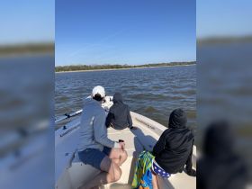A family enjoys a day on the water, seated on a boat while taking in the scenic views — perfect for fishing trips and outdoor adventures.