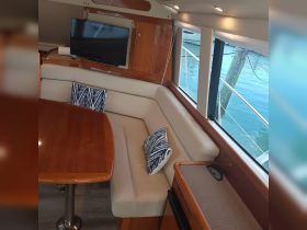 A cozy interior view of a boat's cabin featuring comfortable seating and a dining area, perfect for relaxing while enjoying the scenic waterfront.