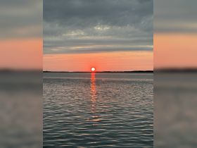 A stunning sunset casts a warm glow over the water, creating a beautiful reflection — perfect for capturing serene moments on the water.